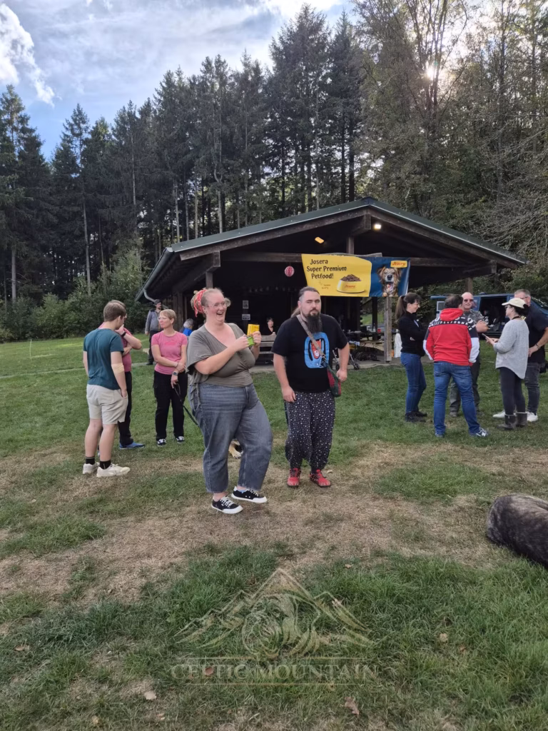 Mehrere Gäste stehen in kleinen Gruppen auf der Wiese vor der Grillhütte mit Josera-Banner.