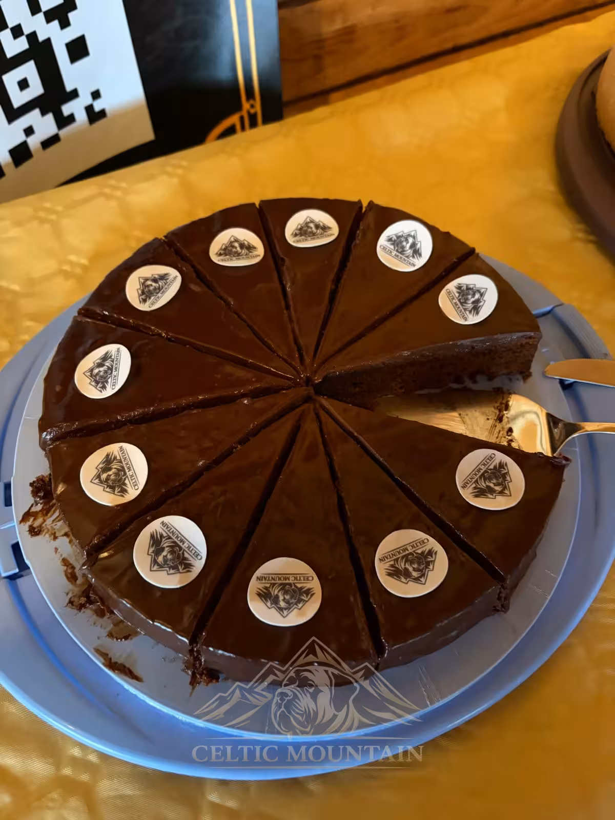 A partly sliced chocolate cake decorated with round Mastiff motifs on the individual pieces.
