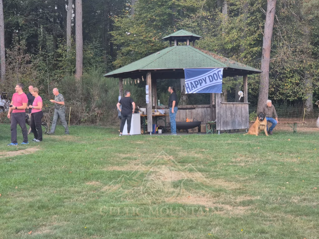 Gäste und Hunde stehen vor einem Holzpavillon mit grünem Dach und Happy-Dog-Banner.