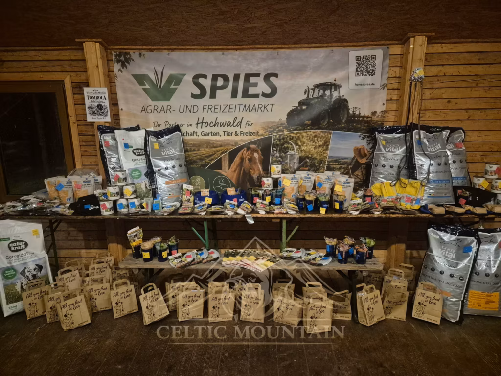 Ein großer Tisch mit Hundefutter, Zubehör und Tombolapreisen steht unter einem Spies-Banner.